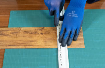 床材に定規を当て、手袋した状態でカッターを使ってカットしている様子